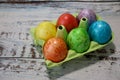 Colorful easter eggs in a egg carton box on wooden kitchen table close up Royalty Free Stock Photo