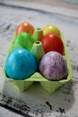 Colorful easter eggs in a egg carton box on wooden kitchen table close up Royalty Free Stock Photo