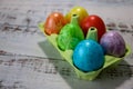 Colorful easter eggs in a egg carton box on wooden kitchen table close up Royalty Free Stock Photo