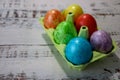 Colorful easter eggs in a egg carton box on wooden kitchen table close up Royalty Free Stock Photo