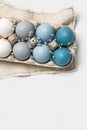 Colorful Easter eggs and flowers decor in carton pack, blue, green, gray neutral colors, festive chicken egg in paper