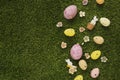 Colorful Easter eggs, flowers and rabbit figurines on a grassy lawn with space for your text Royalty Free Stock Photo