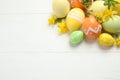 Colorful Easter eggs and flowers on wooden table, flat lay. Space for text Royalty Free Stock Photo