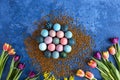 Colorful Easter eggs on golden decorative rocks and tulips. Dark blue background. Holiday decorations, Easter concept background