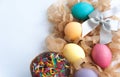 Colorful easter eggs on hay, easter cake and silver bow on white background. Copy space Royalty Free Stock Photo