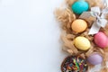 Colorful easter eggs on hay, easter cake and silver bow on white background flat lay. Copy space. Top view Royalty Free Stock Photo