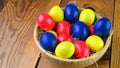 Colorful easter eggs lie in a plate on a straw on a wooden table. Royalty Free Stock Photo