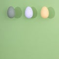 Colorful Easter eggs on a light green background with copy space with a strong shadow. Minimal Easter scene