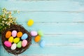 Colorful Easter eggs in nest with flower on rustic wooden planks background in blue paint. Royalty Free Stock Photo