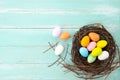 Colorful Easter eggs in nest with flower on rustic wooden planks background in blue paint. Royalty Free Stock Photo