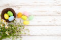 Colorful Easter eggs in nest with flower on rustic wooden planks background in white paint Royalty Free Stock Photo