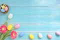 Colorful Easter eggs in nest with flowers on blue wooden background. Royalty Free Stock Photo