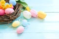 Colorful Easter eggs in nest with flowers on blue wooden background. Royalty Free Stock Photo