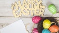Colorful Easter eggs in the nest with text happy easter on white wooden background. Easter holiday concept, flat lay, top view. Royalty Free Stock Photo