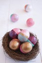 Colorful Easter eggs in a nest on white table. Hunting eggs concept. Copy space