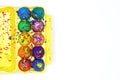 Colorful Easter eggs painted with gouache in yellow egg box isolated on white background, top view copy space Royalty Free Stock Photo