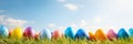 Colorful Easter eggs in a row, decorated with spring flowers and long grass, with bright green bokeh background Royalty Free Stock Photo