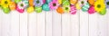 Colorful Easter eggs and spring flowers top border against a white wood banner background Royalty Free Stock Photo