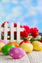 Colorful Easter eggs and white fence on nature background Royalty Free Stock Photo