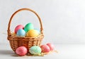 Colorful Easter Eggs in Wicker Basket with Straw Nest on Neutral Background Royalty Free Stock Photo