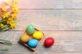 Colorful easter eggs in wood box, yellow narcissus on wood Royalty Free Stock Photo