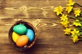 Colorful easter eggs in wood bucket with yellow narcissus Royalty Free Stock Photo