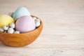 Colorful Easter eggs in a wooden bowl on a wooden background, place for text Royalty Free Stock Photo