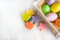 Colorful easter eggs in wooden box and homemade fondant covered flower cookies on a white wood background Royalty Free Stock Photo