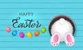 Colorful Easter greeting card. Easter bunny in a burrow with a tail and painted eggs with an ornament on a wooden background with