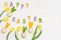 Colorful eggs with cloth ears as Easter bunny and multicolor letters Happy Easter. Bright yellow spring flowers tulip Royalty Free Stock Photo