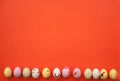 Colorful eggs laid out in a row on a coral background. copy space