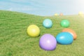 Colorful eggs in a meadow on a sunny day against the blue sky. Multicolored painted easter eggs on grass, lawn. Concept