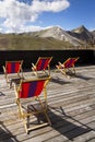 Colorful empy deckchairs on terrace with Italian Alps mountains