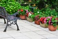 Colorful English patio area with planters and iron bench.