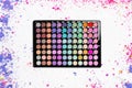 Colorful eyeshadow palette with scattered eyeshadow powder on white background