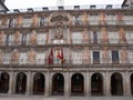 Colorful facade and arches of a building in the Plaza Mayor with the flags of Spain, City Hall and Community of Madrid