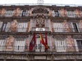 Colorful facade of a building in the Plaza Mayor with the flags of Spain, City Hall and Community of Madrid