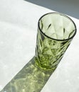 Colorful faceted geometric glass and drink, empty, green, view angle, a shadow from the glass