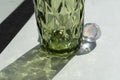 Colorful faceted geometric glass and drink, empty, green, view angle, a shadow from the glass