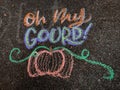 Colorful fall-themed chalk art on a driveway that says, Oh my gourd! with a pumpkin underneath.