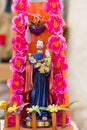 Colorful figure of Saint Joseph holding Child Jesus with pink flowers around