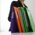 Colorful file folders, arranged vertically on a white surface, include purple, orange, and green.