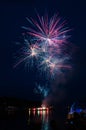 Fireworks launched from a river barge with lights reflected in the water. Royalty Free Stock Photo