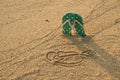 Colorful flip flops and heart shape on white sand beach Royalty Free Stock Photo