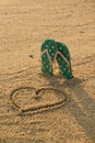 Colorful flip flops and heart shape on white sand beach Royalty Free Stock Photo