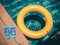 Flip flops at the poolside and floating ring on the water