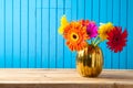 Colorful flower bouquet in golden vase on wooden table