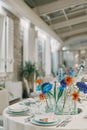 Colorful flowers in vases stand on a set table in a restaurant Royalty Free Stock Photo