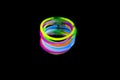 Colorful fluorescent light neon glow stick bracelet strap wristband on mirror reflection black background