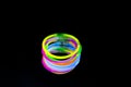 Colorful fluorescent light neon glow stick bracelet strap wristband on mirror reflection black background